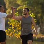 Two men in fitness gear greeting each other outdoors